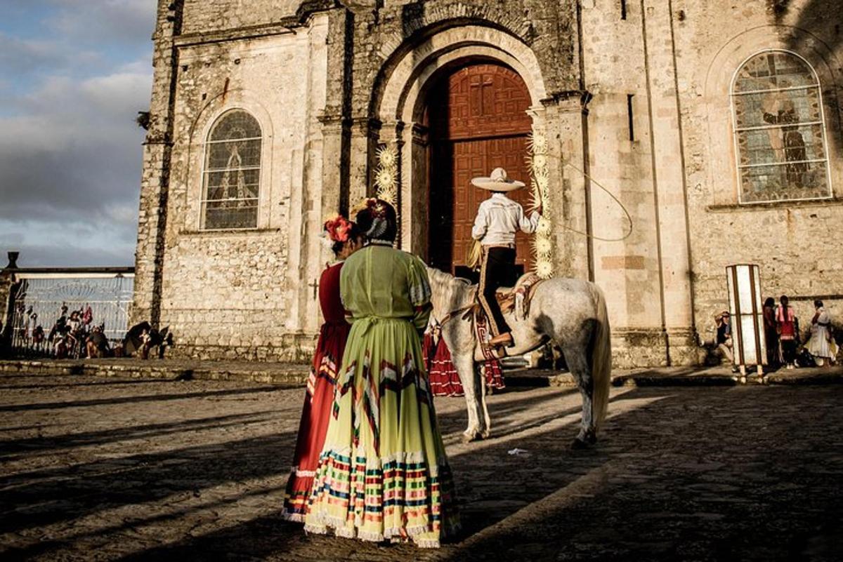 a woman in a dress standing in front of a building with a horse