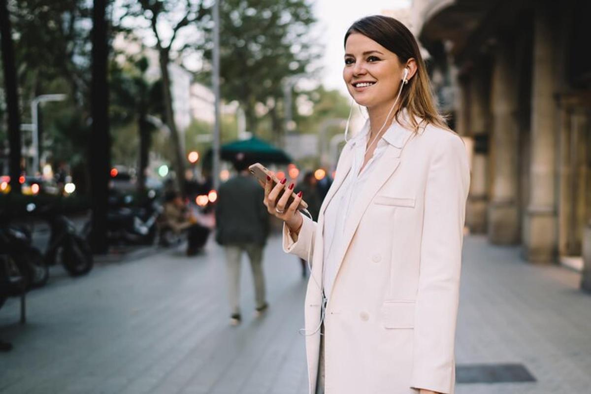 žena v bílém obleku se dívá do svého mobilního telefonu