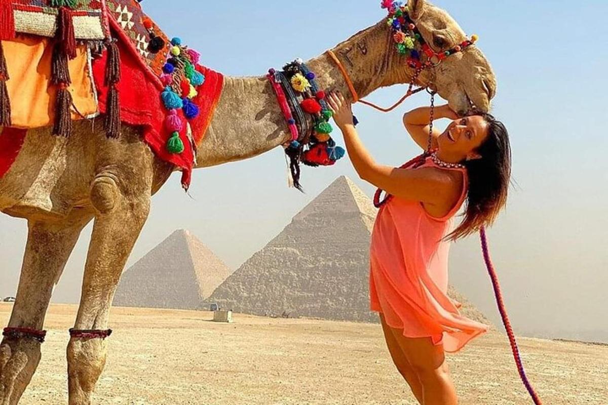 امرأة تقف بجانب جمل أمام الأهرامات