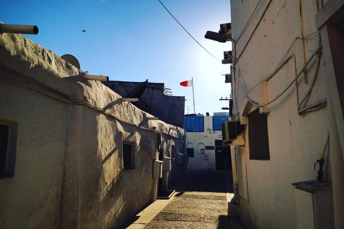 an alley between two buildings with a flag in the distance