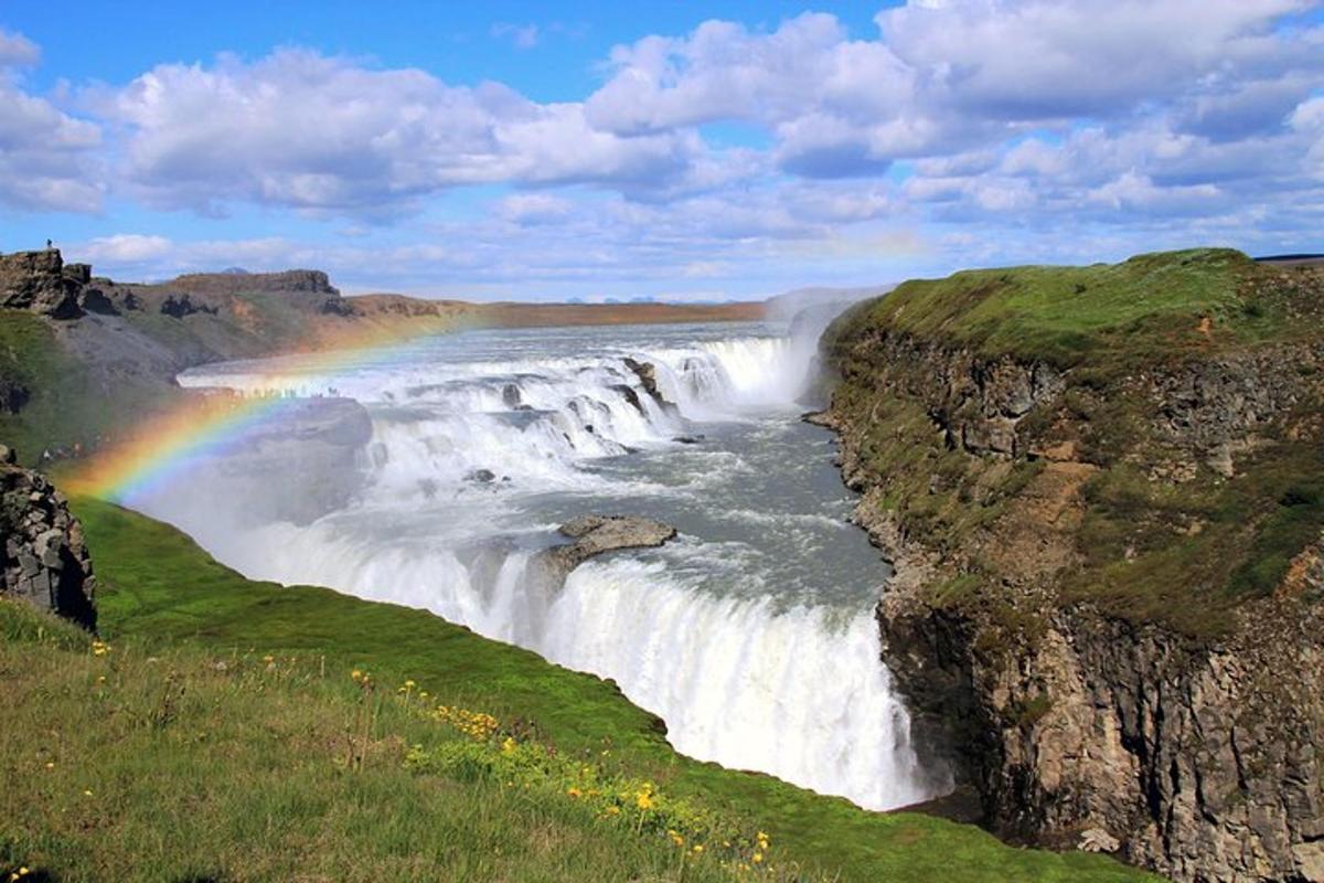 een regenboog boven een waterval met een rivier