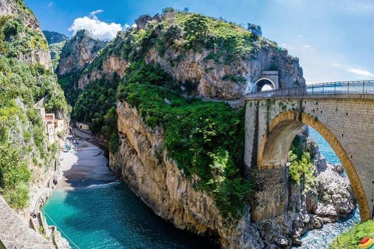 un puente sobre un río al lado de una montaña
