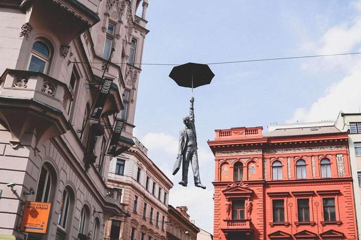 socha muže visícího z budovy s deštníkem