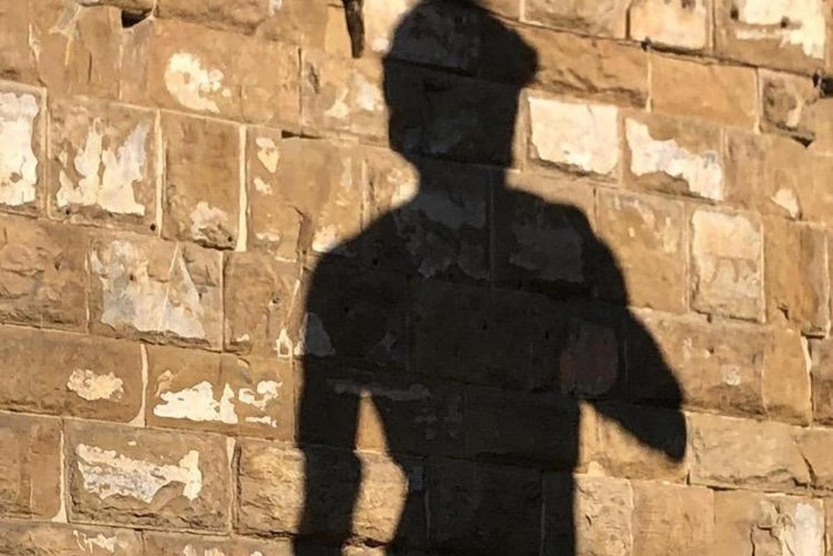 a sombra de um homem em uma parede de tijolos