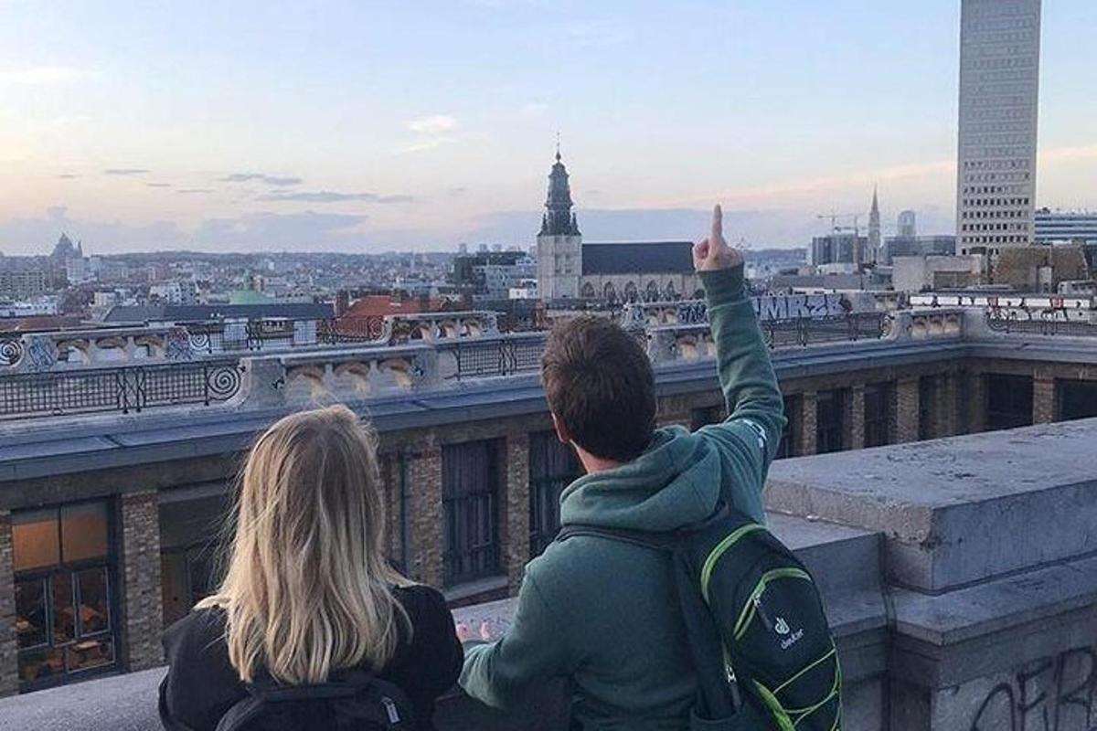 Dos personas sentadas en una cornisa mirando una ciudad