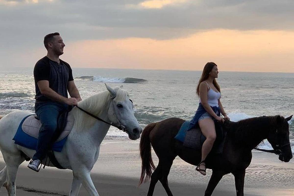 muž a žena jedoucí na koních na pláži