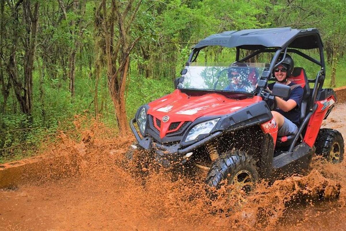 un uomo che guida un quad rosso nello sporco