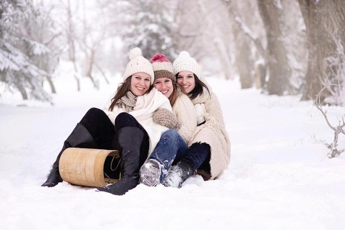 雪の中に樽を持って座っている3人の女の子