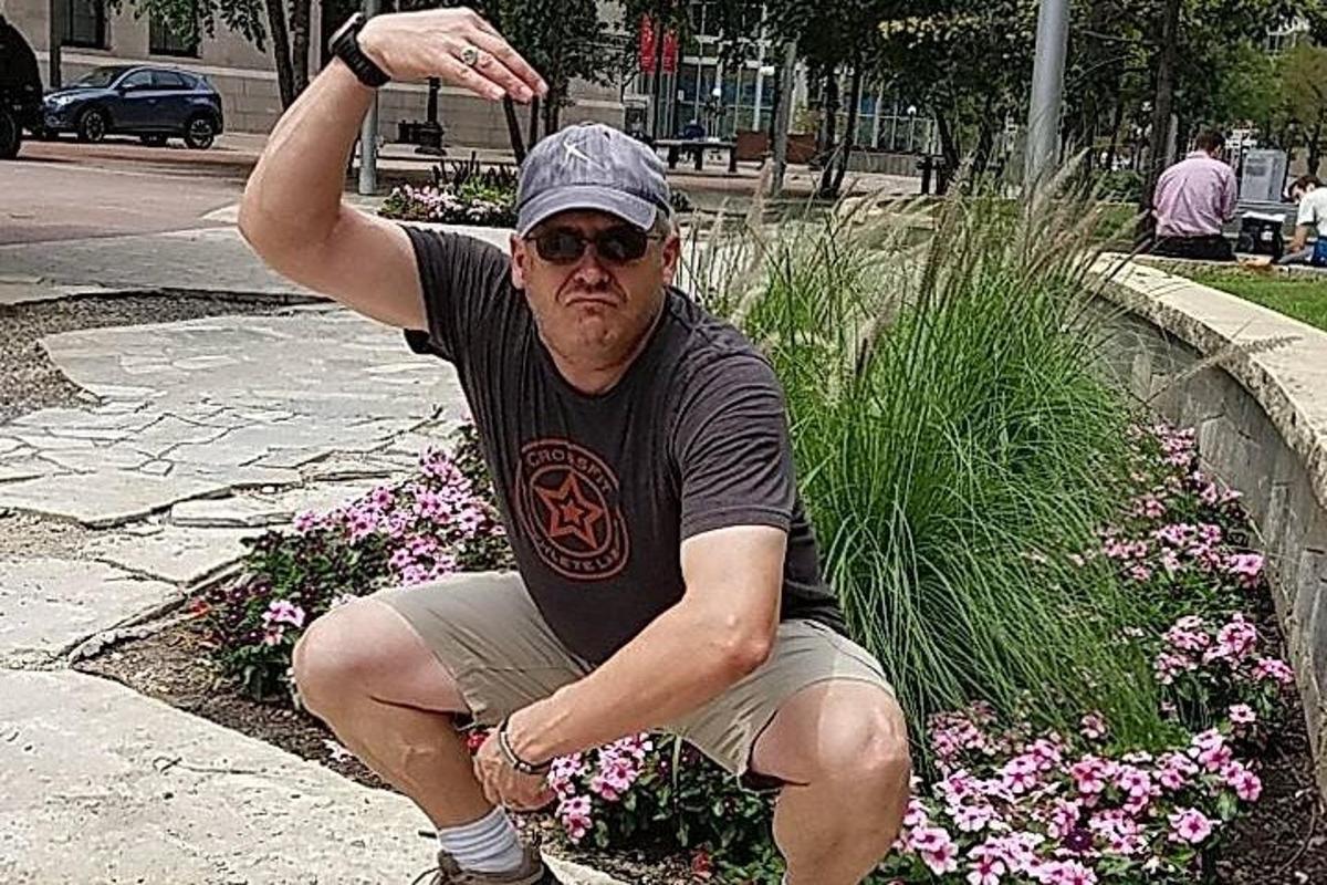 a man sitting on a curb in front of flowers