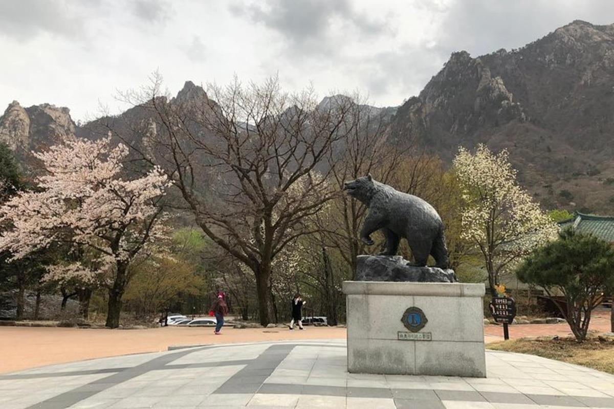 a statue of a bear in a park with mountains in the background