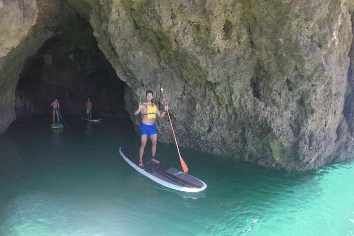 un bărbat stă pe o placă de paddle într-o peșteră