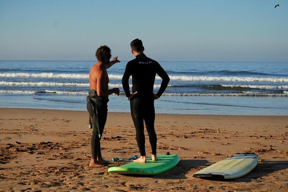to mænd står på stranden med surfbrætter på stranden