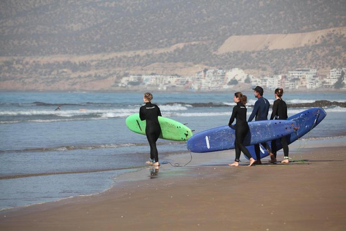 un gruppo di persone che camminano sulla spiaggia con le tavole da surf
