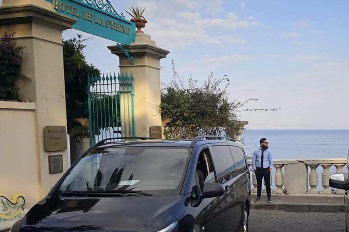 um homem parado ao lado de um carro estacionado perto do oceano