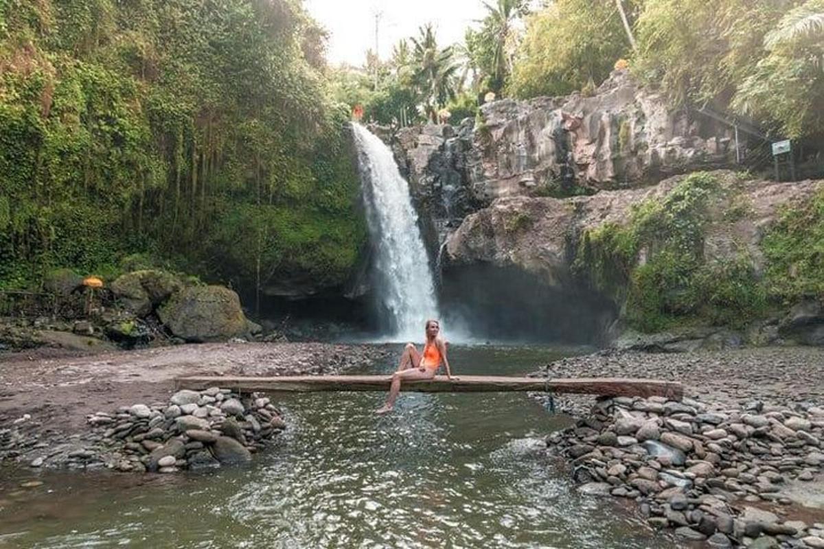 un hombre sentado en el agua frente a una cascada