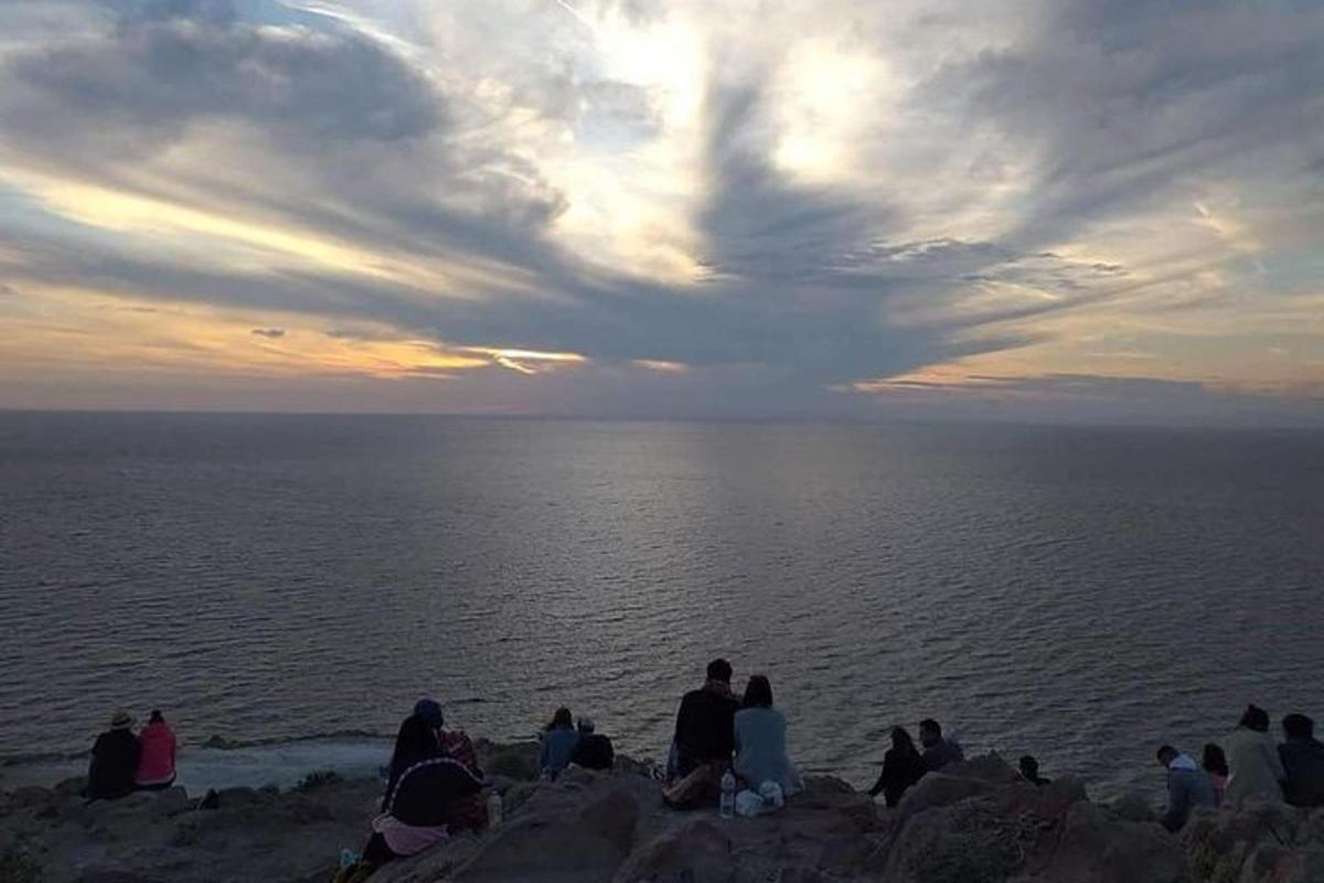 un grup de persones assegudes en una roca prop de l'oceà