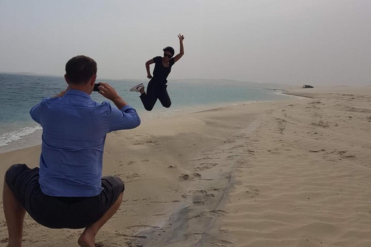 a man taking a picture of a person jumping on the beach