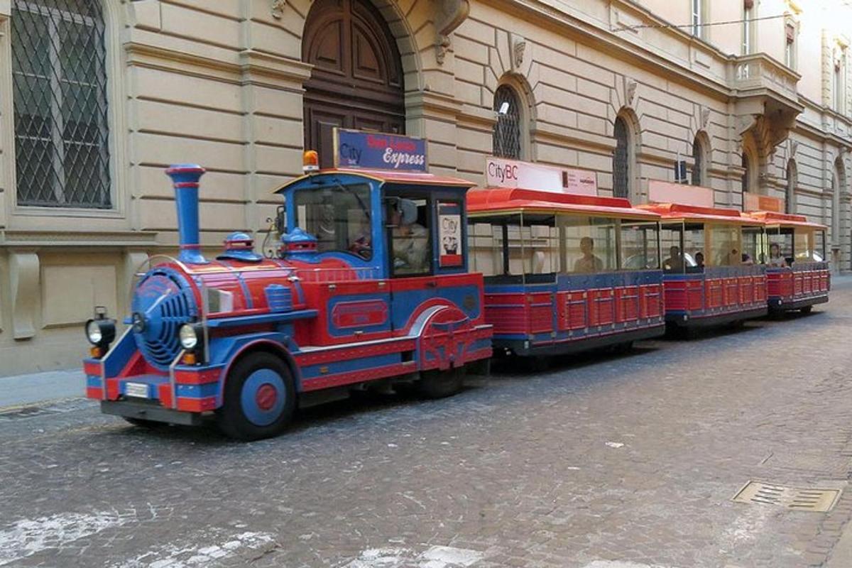 a red and blue train on a street next to a building
