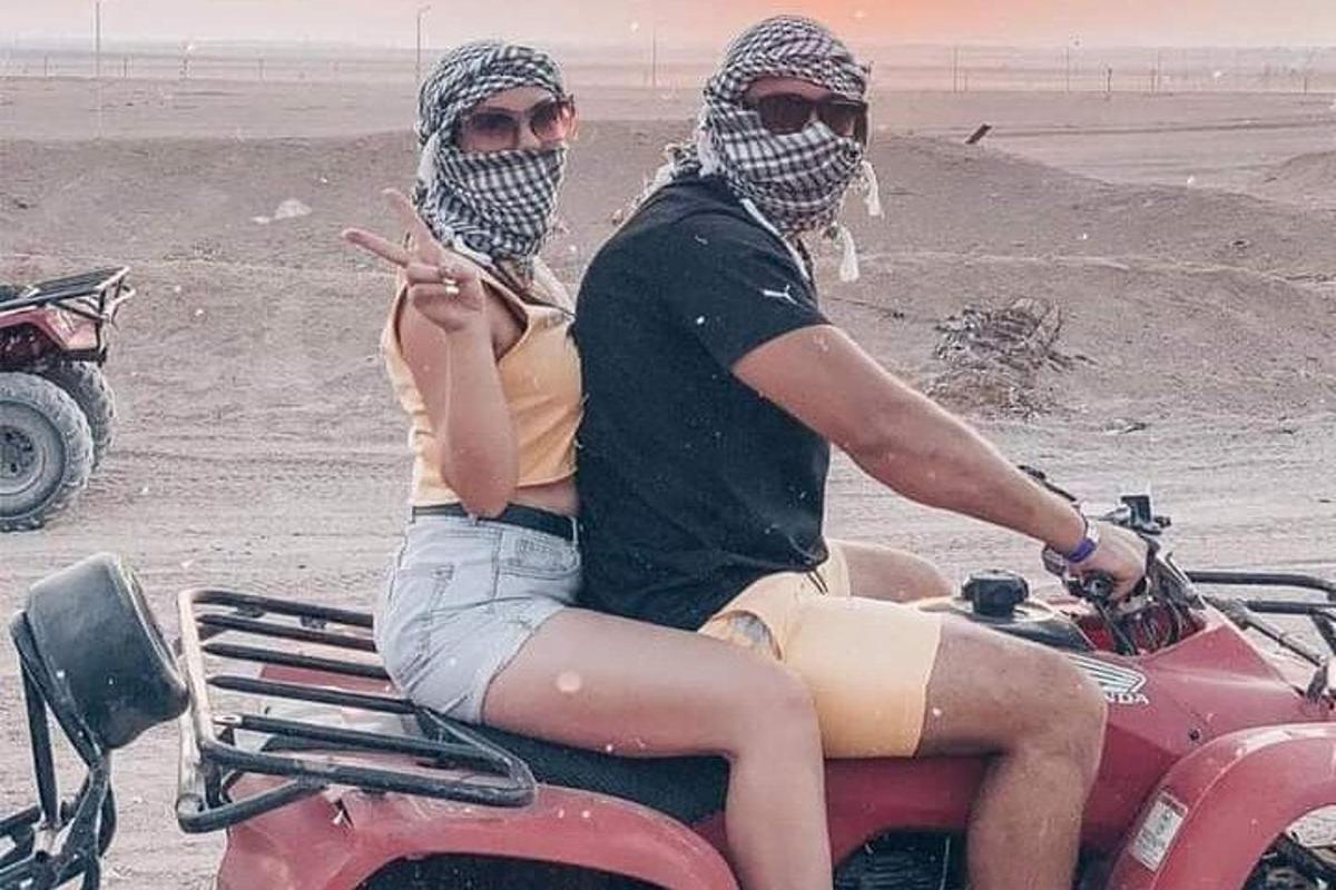 seorang pria dan wanita duduk di atas sepeda motor di pantai