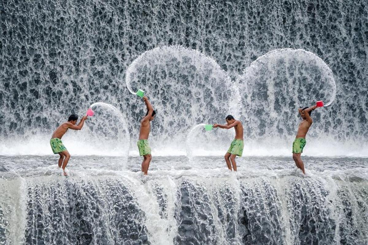 a group of men standing in front of a waterfall