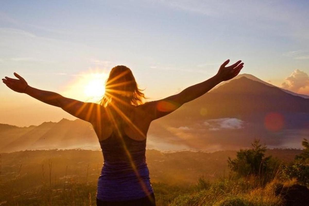 a woman with her arms outstretched in front of a mountain