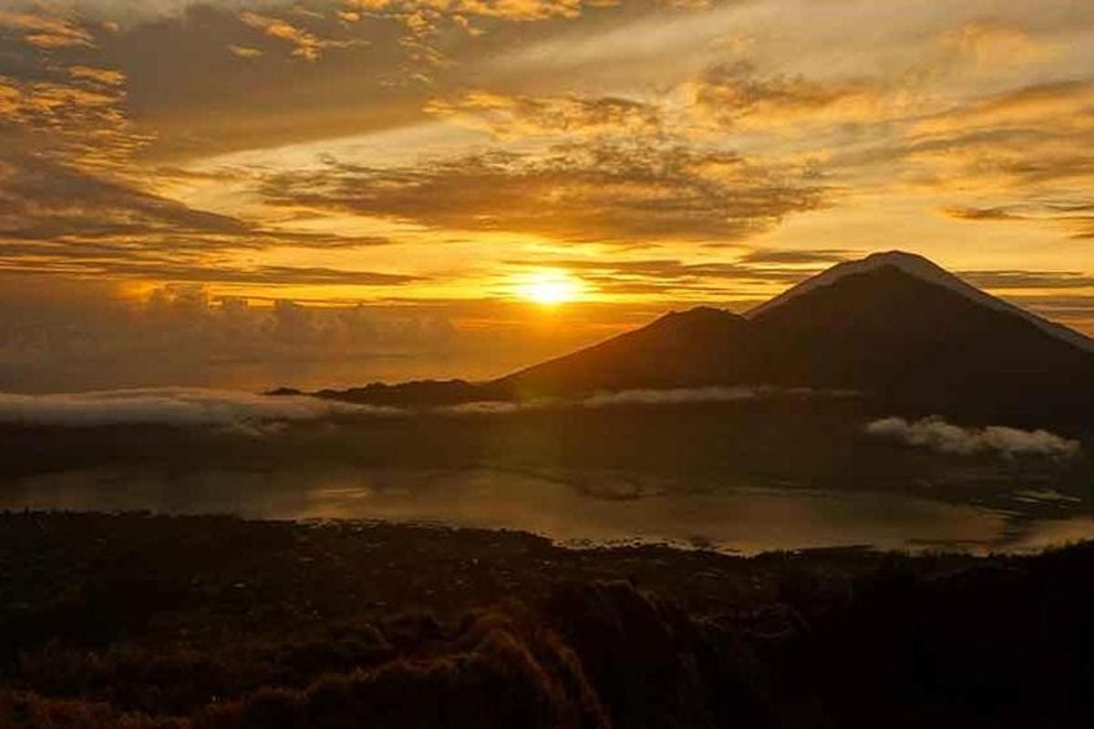 a sunset over a mountain with a lake in front
