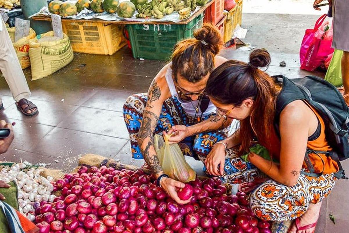 Două femei se uită la o grămadă de fructe la o piață