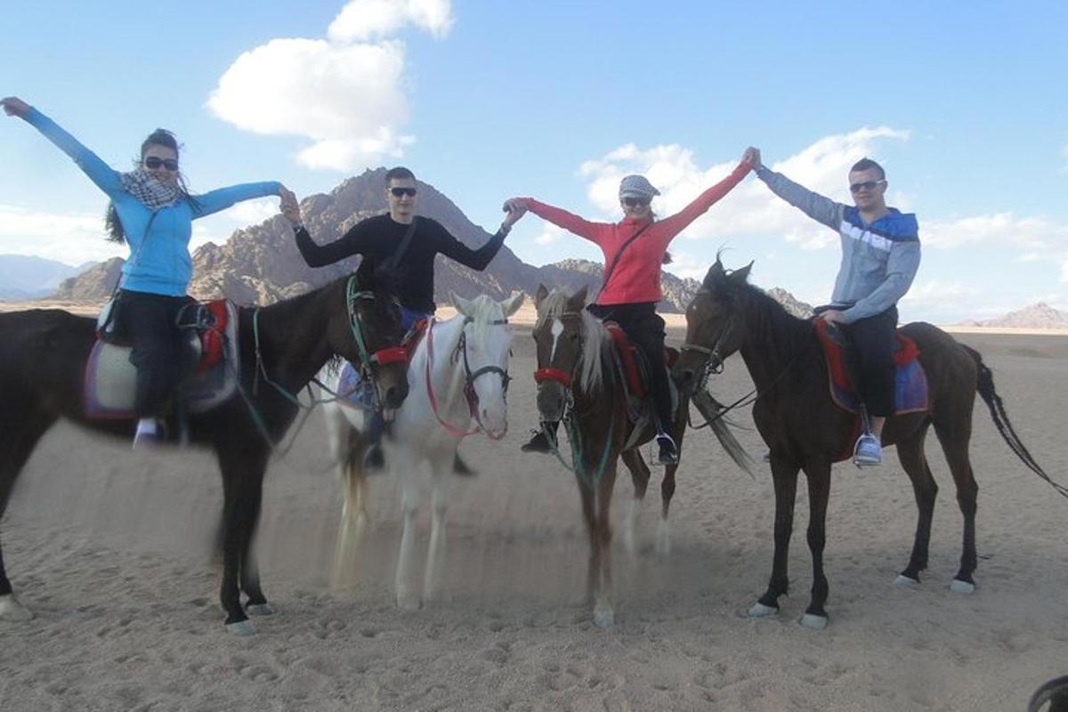 a group of four people riding horses in the desert