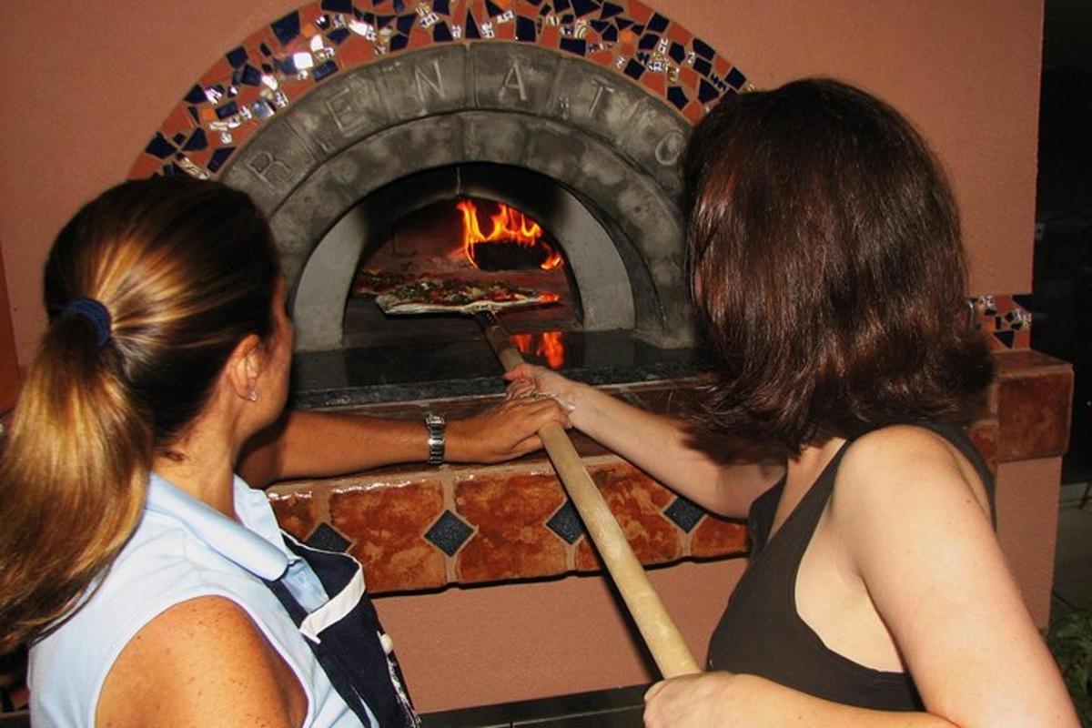 due donne che mettono una pizza in un forno di mattoni
