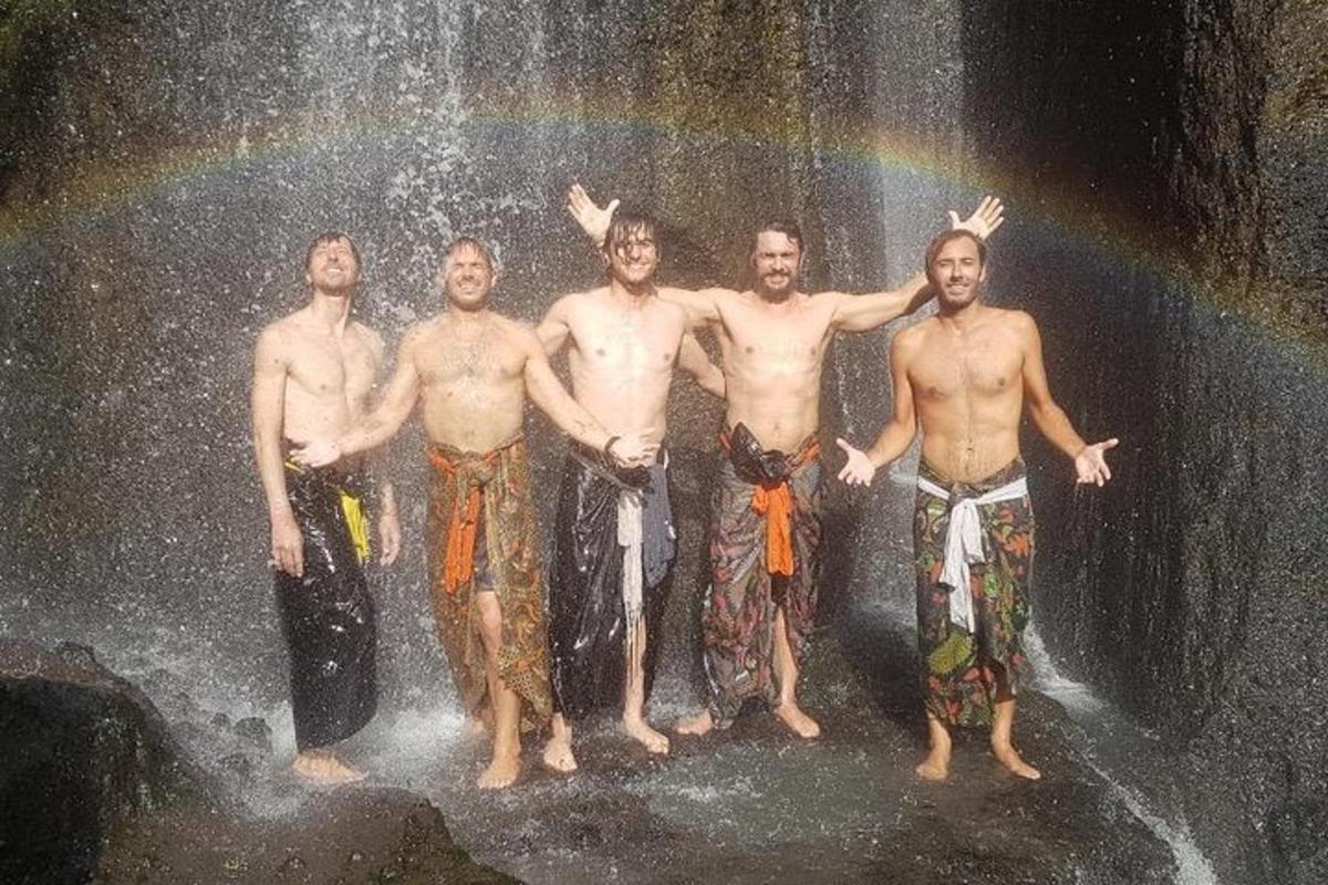 sekelompok pria berdiri di depan air terjun