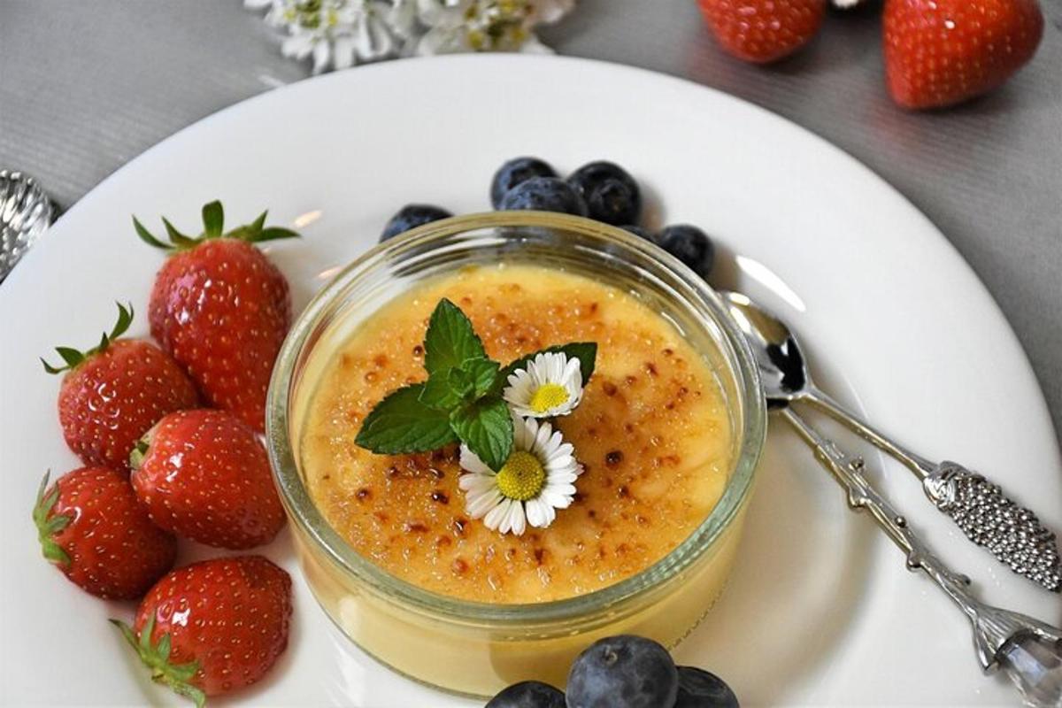 a jar of fruit jam on a plate with strawberries and blueberries