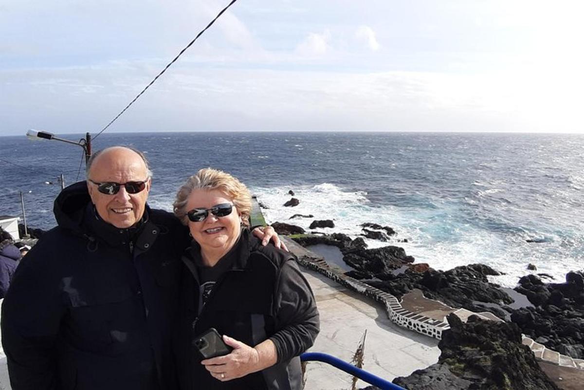 a man and a woman standing next to the ocean