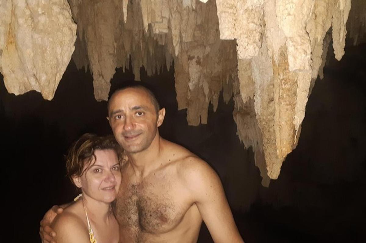 Un hombre y una mujer de pie frente a una cueva.