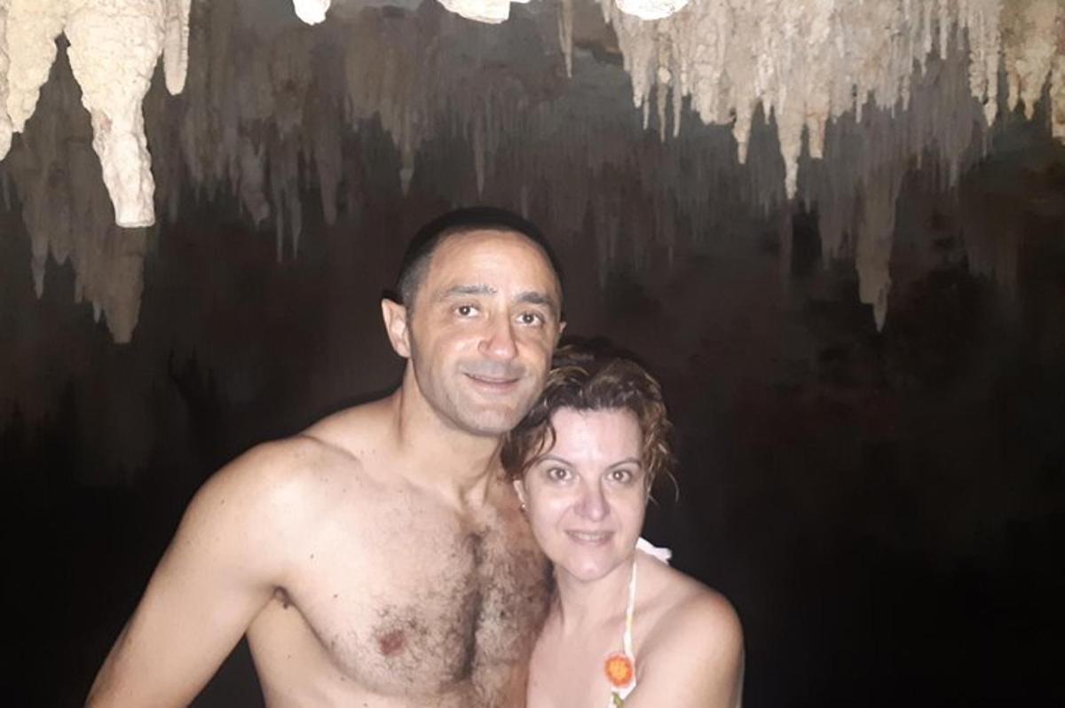 Un hombre y una mujer de pie frente a una cueva.
