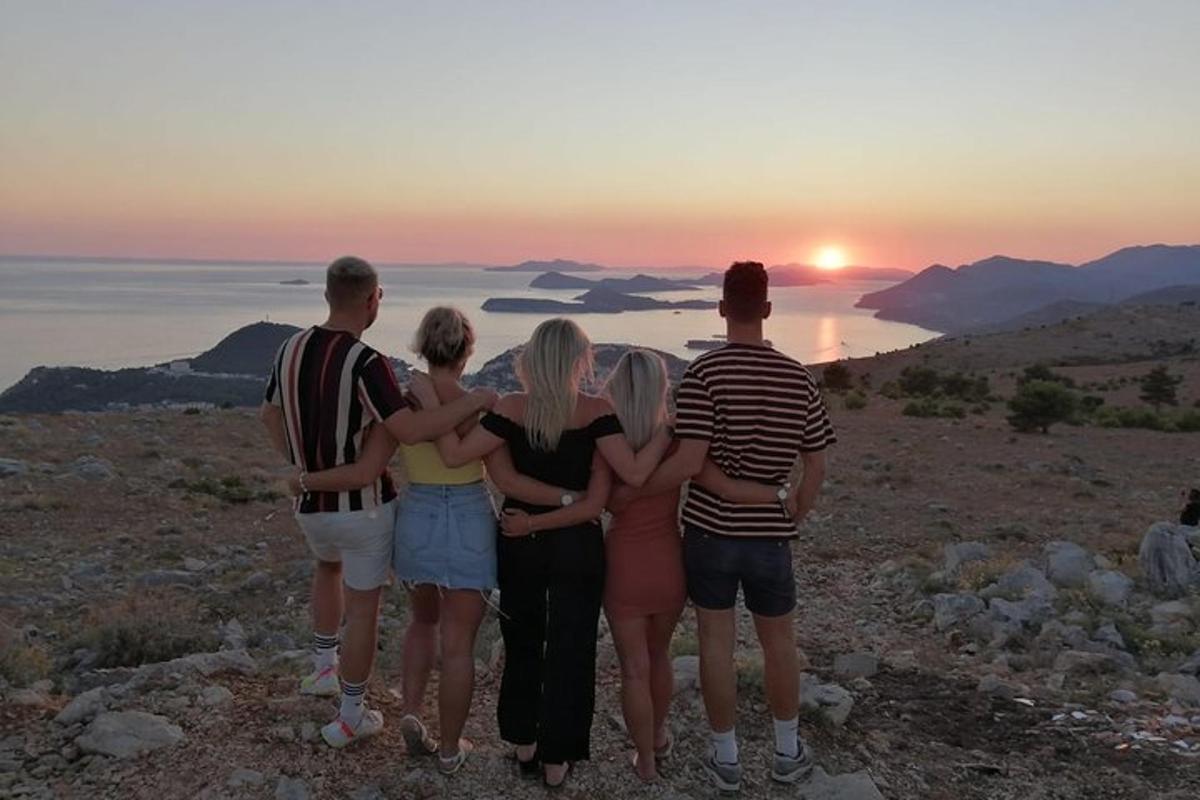 en gruppe mennesker som står på en høyde og ser på solnedgangen