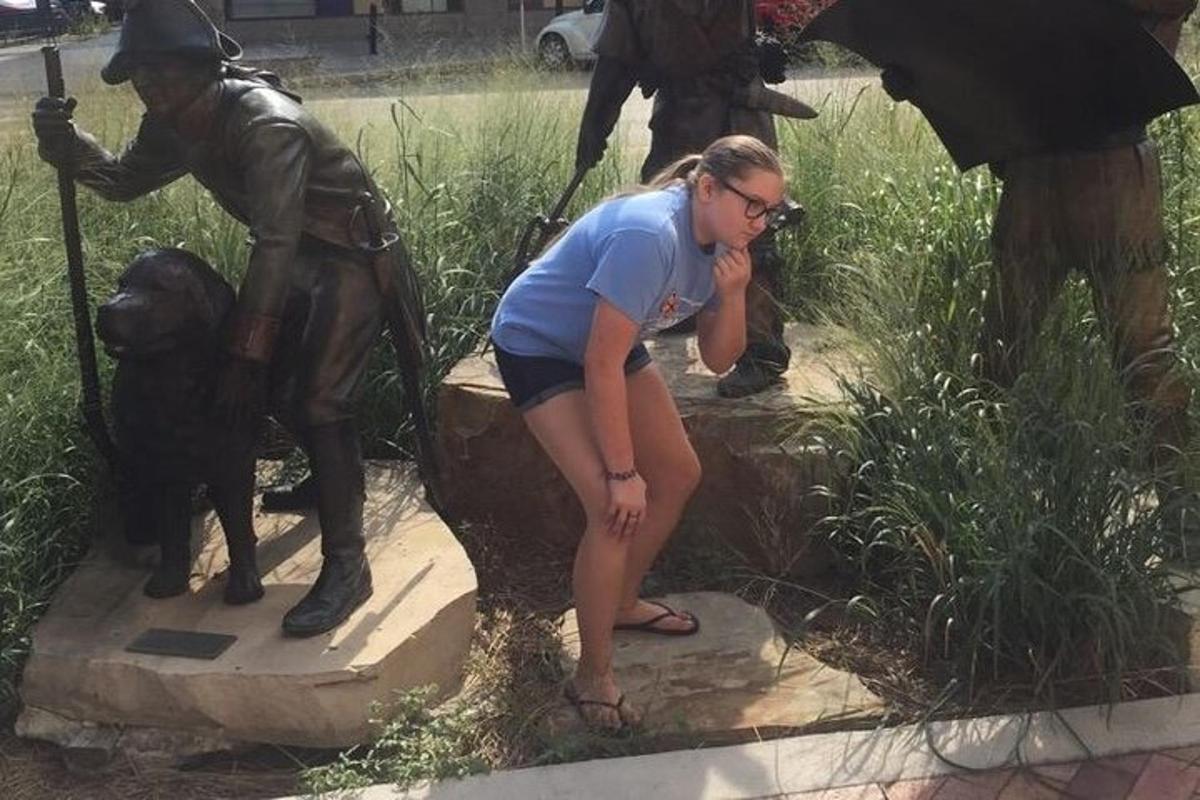 una donna in piedi accanto alla statua di un uomo