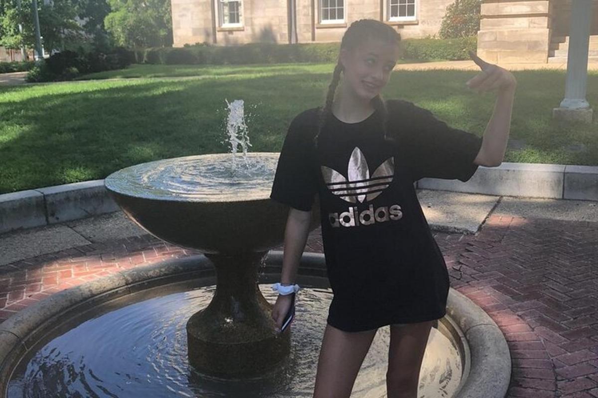 una giovane ragazza in piedi davanti a una fontana
