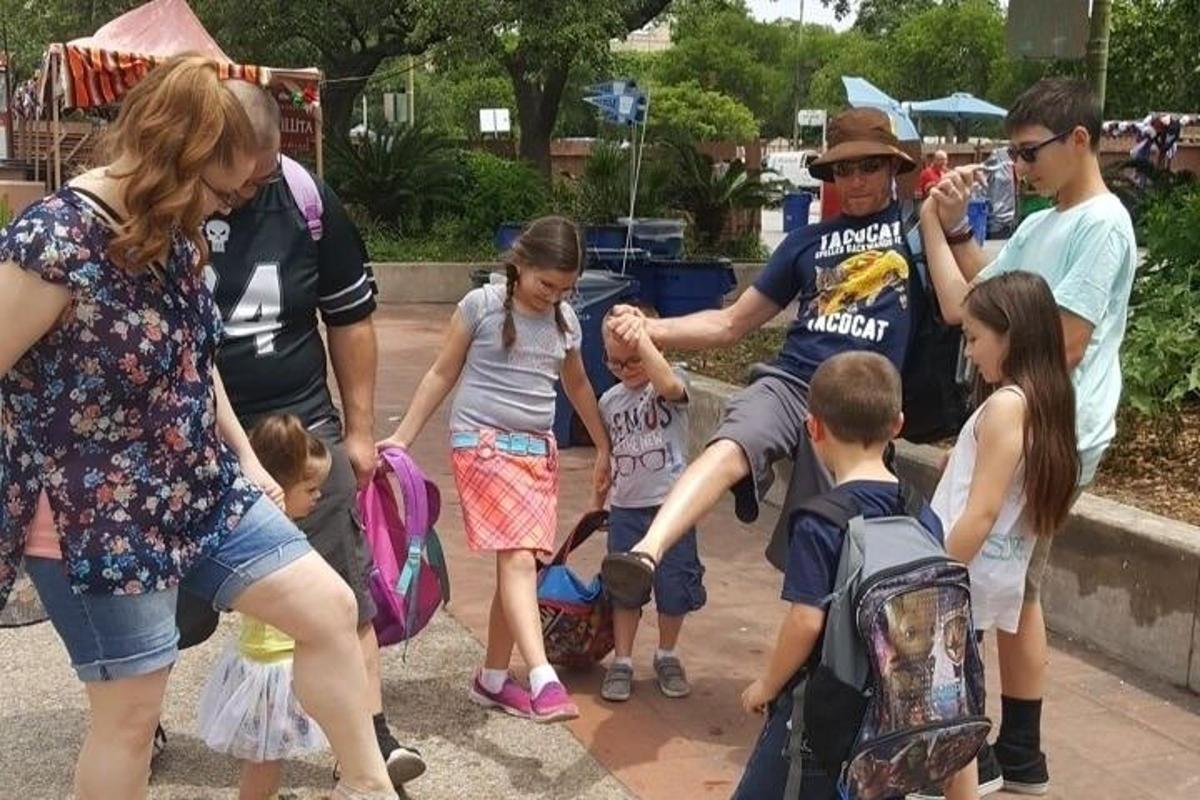 skupina ljudi, ki stojijo okoli skupine otrok