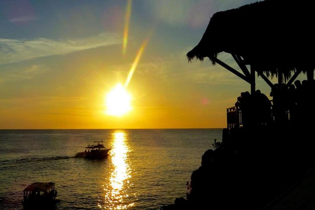 a boat in the ocean with a sunset in the background
