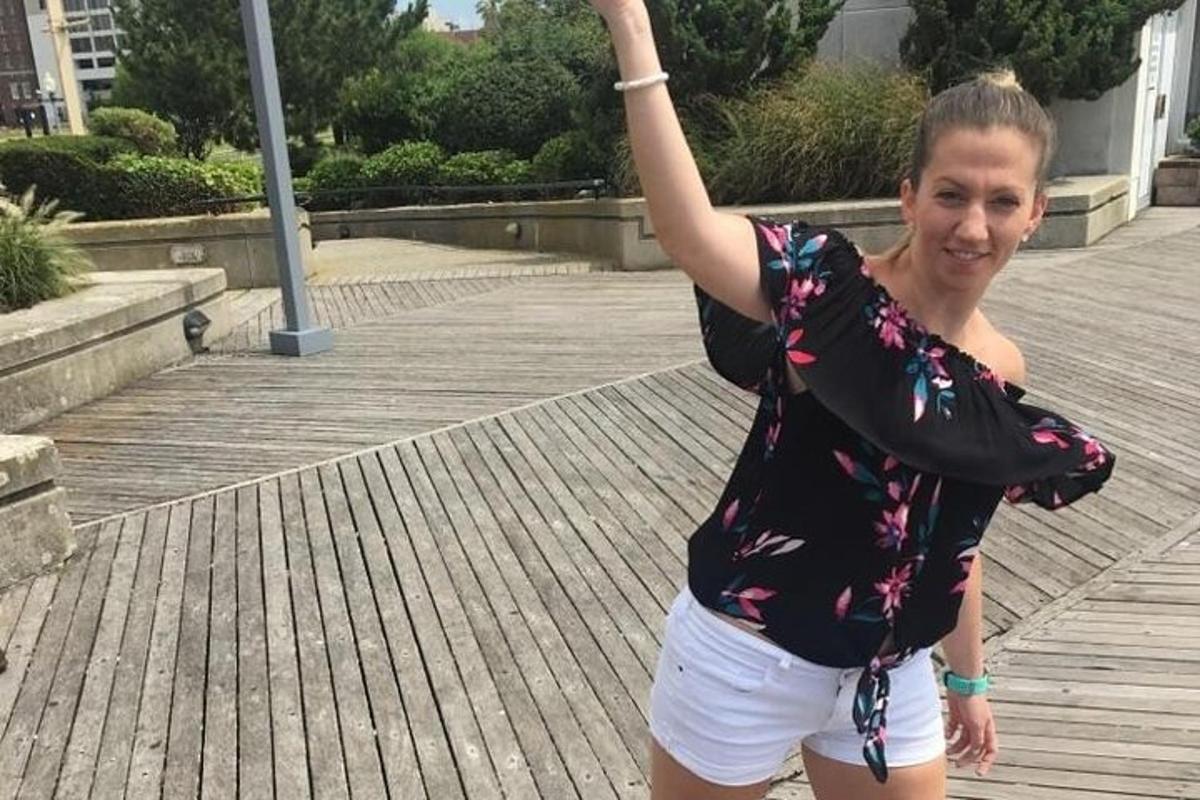 una dona dreta en un passeig marítim amb el braç enlaire