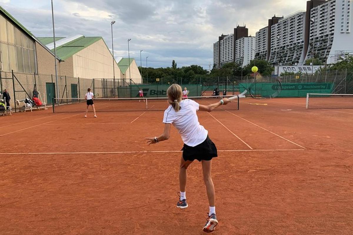dve ženski igrata tenis na teniškem igrišču