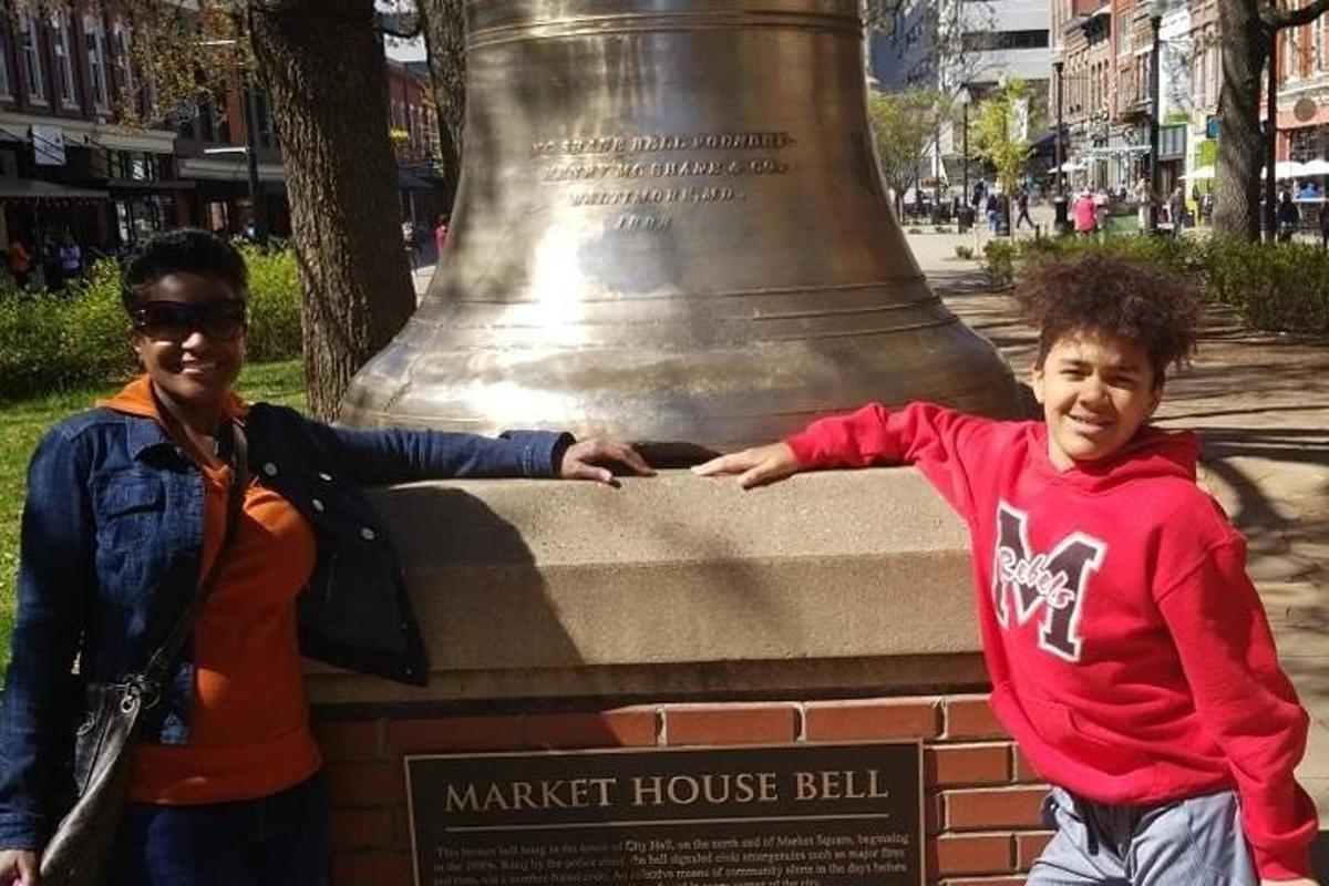 dva mladí lidé stojící před velkým zvonem