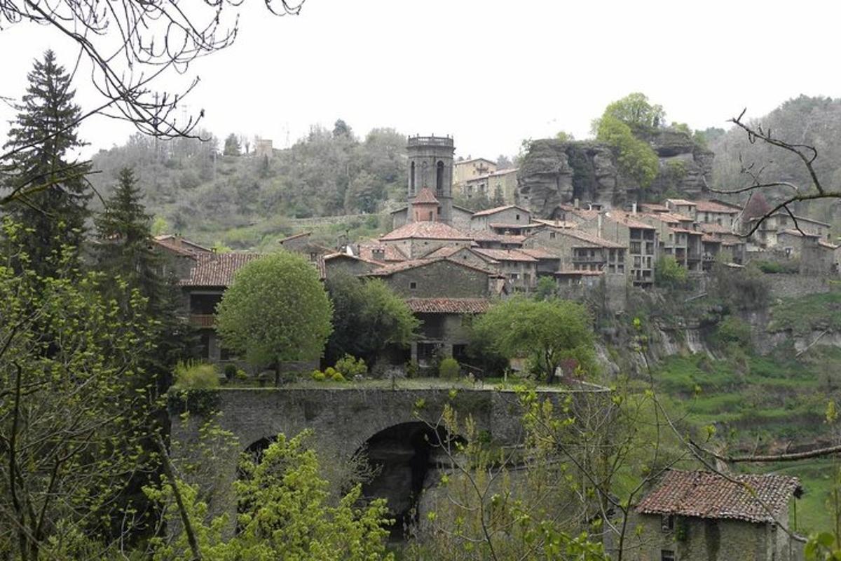 Un pueblo en una colina con un puente y edificios.