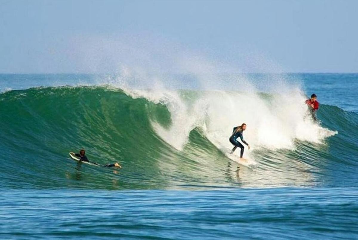three people riding a wave on surfboards in the ocean