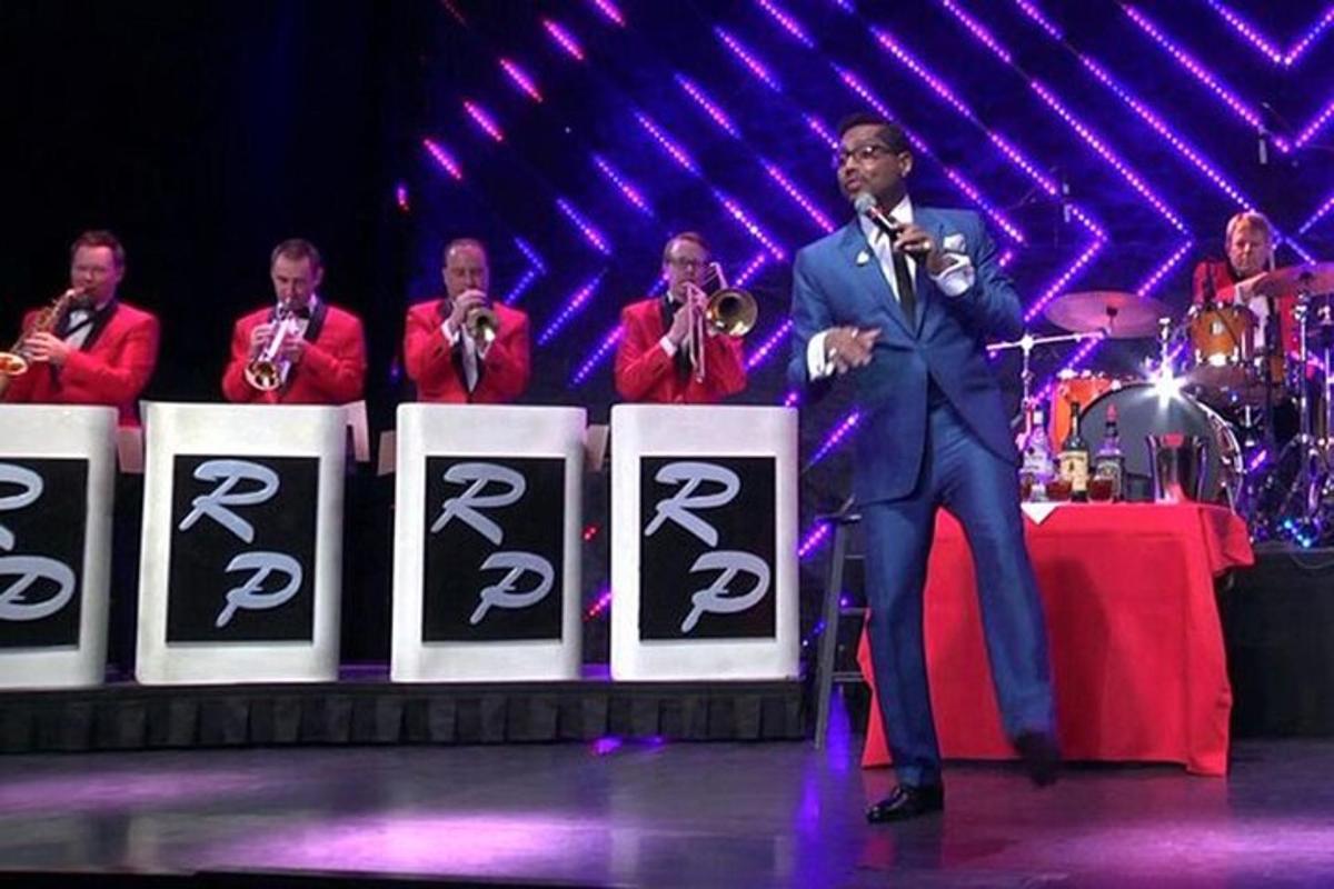 a man in a suit standing on a stage singing