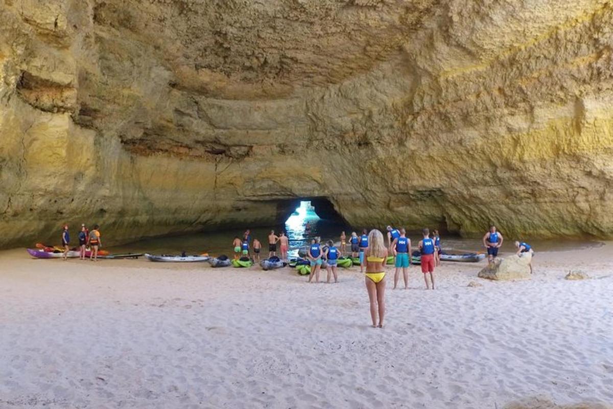 skupina ljudi, ki stojijo na plaži blizu jame