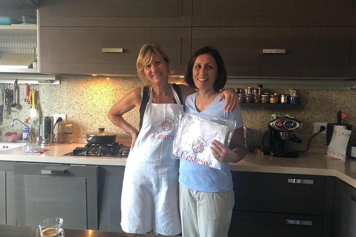 two women standing in a kitchen holding a bag