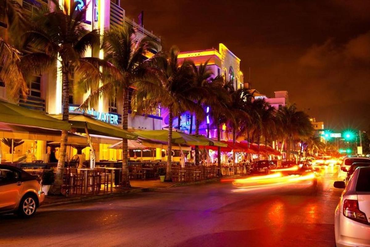 a city street at night with palm trees and buildings