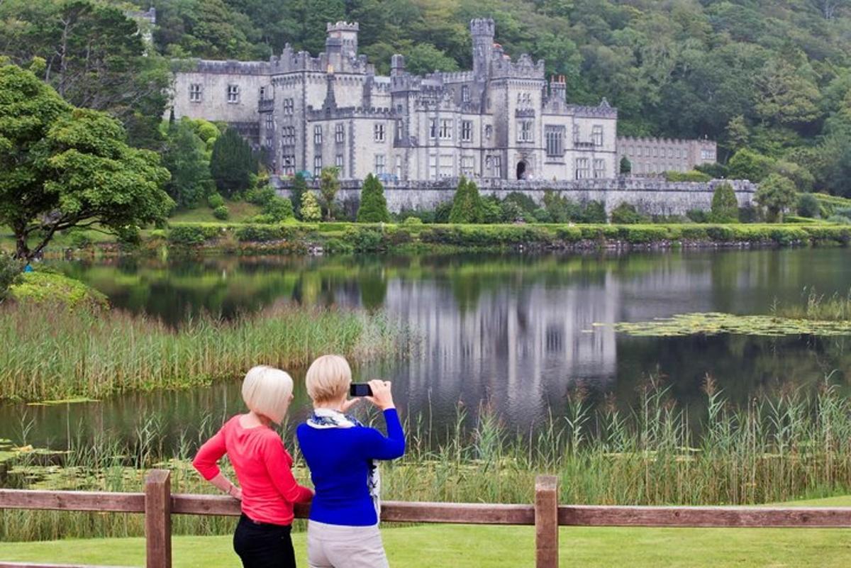 due donne che scattano una foto di un castello sopra un lago