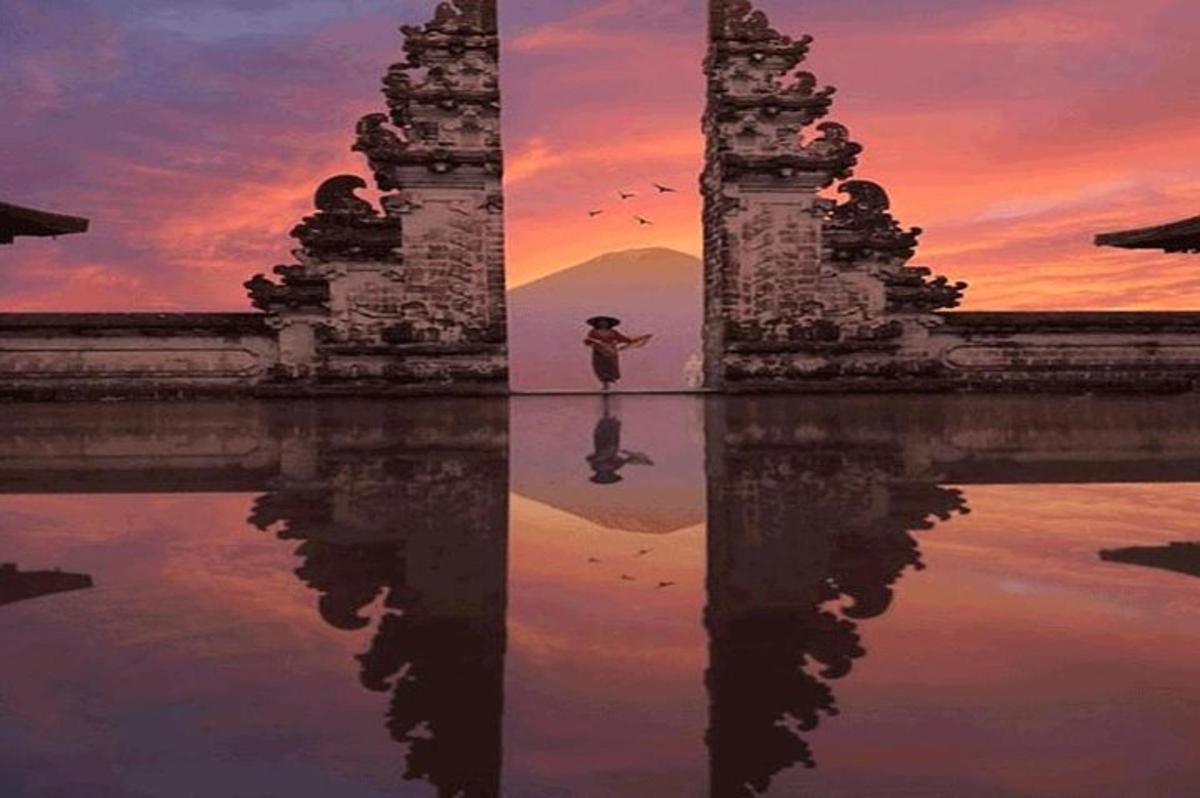 eine Frau steht vor einem Schloss mit seiner Spiegelung im Wasser